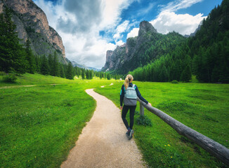 Wall Mural - woman with backpack on the trail in beautiful alpine mountain valley at colorful sunset in summer. d