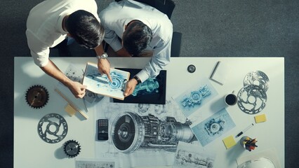 Top down aerial view of manager sitting while answer question about jet engine. Professional engineer looking at turbine engine or electronic generator while colleague asking question. Alimentation.