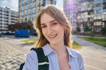 Selfie portrait of young happy blonde female looking at camera outdoor