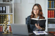 © amnaj - Lawyer is sitting at her desk reading a law book while working on a case in her office