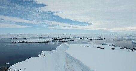 Wall Mural - Antarctica majestic landscape, snow covered coast aerial drone view. Polar frozen ocean. Antarctic shoreline. Glacier, icebergs and ice floes floating cold water. South Pole travel and exploration.