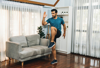 Wall Mural - Athletic and sporty man running posture at home body workout exercise session for fit physique and healthy sport lifestyle at home. Gaiety home exercise workout training.