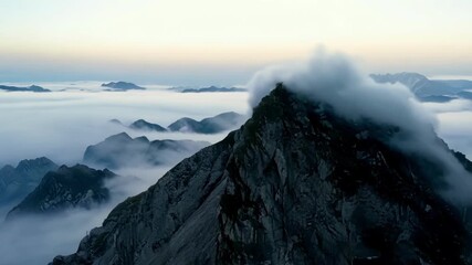 Wall Mural - The serene beauty of the mountain peak as clouds of mist glide over its rocky surface.