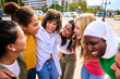 © CarlosBarquero - Group of multicultural young only women standing hugging in circle laughing and looking each other outdoor. Gen z female community people embracing together having fun and enjoying girls friendship