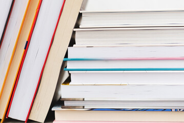 Stack of books with colorful bookbindings against white wall with copy space, book lover