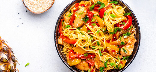 Wall Mural - Egg noodles with stir fried chicken, pineapple, paprika, green onion, ginger, garlic, soy sauce and sesame seeds. White background, top view