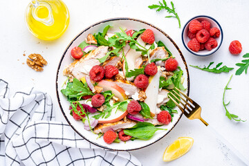 Wall Mural - Delicious summer salad with raspberries, chicken meat, fresh pears, ricotta cheese, red onion, nuts, spinach and arugula, white background, top view