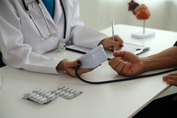 Wall Mural - Doctor using sphygmomanometer with stethoscope checking blood pressure to a patient in the hospital.