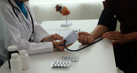 Wall Mural - Doctor using sphygmomanometer with stethoscope checking blood pressure to a patient in the hospital.