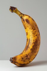 A vibrant yellow banana with brown spots, showcasing its ripe and appealing appearance against a minimalistic background.