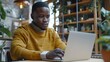 © Generative AI - Focused african american casual businessman sitting at desk using laptop in office copy space : Generative AI
