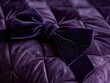 © MINMIN - A close-up of a purple velvet bow tied on a quilted fabric. The bow has a subtle shimmer and adds a touch of elegance to the image.