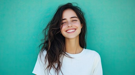 Wall Mural - A happy woman in white casual attire, with a radiant smile, posing in front of an aqua blue-green background, ideal for uplifting portraits