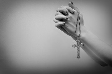 woman hands holding a silver vintage holy cross and prayed for blessings. faith in God concept. black and white tone