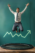 © Ala - Energetic Business Professional Leaps Joyfully on Trampoline As Stock Market Shows Positive Trends