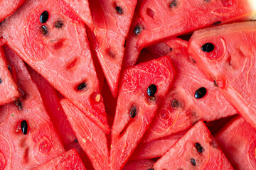 Many fresh red sliced ​​watermelon fills the frame, top view.