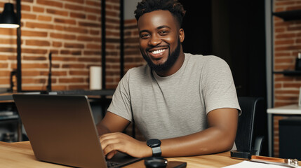 Poster - a happy man sitting at desk working on laptop looking at camera