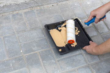 Wall Mural - A person is painting a brick floor with a roller