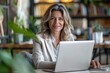 © Spectrum Sculptor - 40s mid age European business woman CEO using laptop application for work sitting at table workspace in office. Smiling Latin Hispanic mature adult professional businesswoman using pc, Generative AI
