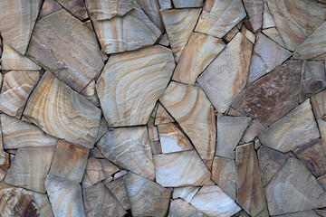 Weathered old stone wall as creative background texture. Natural stone masonry with uneven seams. Rough texture of stone tile wall. Shell rock, slate, granite as background for vintage modern design