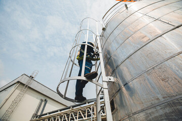 Wall Mural - Male worker climbs up the ladder inspection stainless tank