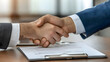 © Steve - Close-Up of Signed Series B Investment Contract on Polished Wood Table with Celebratory Handshake in Background