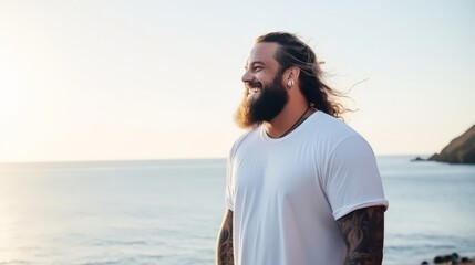 Male model smiles while wearing a white tee by the serene ocean