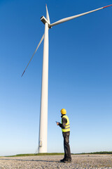 Canvas Print - Engineer with digital tablet controls wind turbines