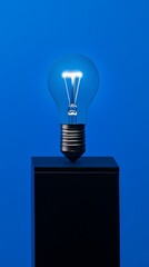 Aufkleber - Light bulb on black pedestal against blue background, studio shot. Innovation and energy concept