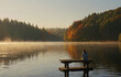 © Nargiz - A single individual sits on a wooden dock at sunrise, bathed in golden light. The tranquil lake and autumn trees provide a peaceful setting for introspection.