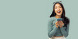 © Nutlegal - Asian cheerful young woman in a casual outfit joyfully interacts with her smartphone, expressing excitement and positivity Amazed girl using device gadget app smm post digital connection and happiness