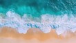 © pinporn manosri - Drone shot of a beautiful beach with clear blue ocean and splashing waves, highlighting the sunny Mediterranean shore ideal for summer tourism
