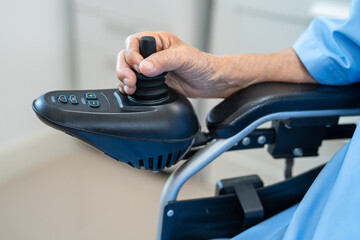 Asian senior woman patient on electric wheelchair with remote control at hospital, healthy strong medical.