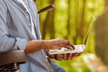 Poster - Always in touch. Unrecognizable african american man using laptop while riding bicycle in forest