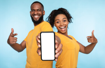 Poster - Use this new application. Cheerful black couple pointing at smartphone with blank screen, recommending mobile app, advertising your website, mockup for design. Selective focus