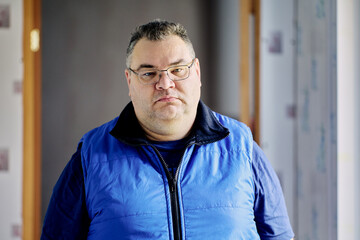 Gloomy large built European man of about 40 wearing glasses.