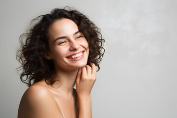 Wall Mural - beautiful female model smiling looking into the camera on grey background, portrait of a woman