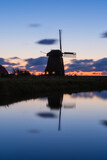 Fototapeta  - Windmill in the Netherlands. Historical buildings in the Netherlands. Reflections on the surface of water. Image for postcards and background. Landscape during sunset.