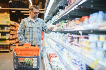 Mature man buying groceries at the supermarket. Consumerism concept