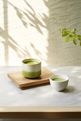 Japanese Matcha Green Tea Latte in Ceramic Cups with Wooden Saucer on Table Composition, Natural Light and Shadow. Minimal Interior. Minimalism. Food Photography.