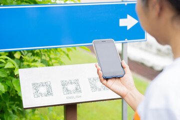 A traveler female hand scans an information point on a natural route.