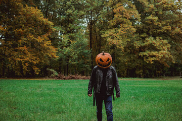 eerie looking stranger in the forest wearing a halloween pumpkin costume