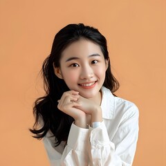 Wall Mural - Portrait of a Young Asian Woman Smiling in a White Shirt Against a Peach Background