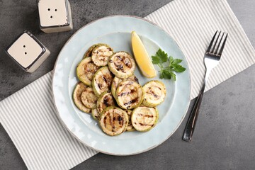 Canvas Print - Tasty grilled zucchini slices served on grey textured table, flat lay