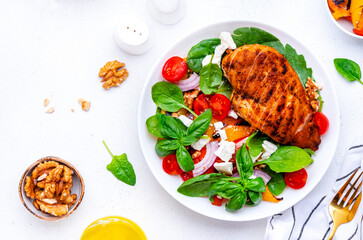 Wall Mural - Summer grill salad with paprika and chicken meat, soft cheese, tomatoes, walnut, red onion and lettuce, white background, top view