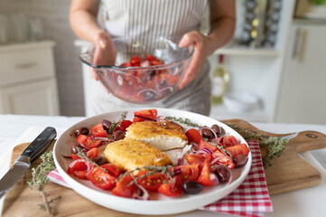 Fresh and homemade breaded feta cheese with tomato olive salad prepared by woman´s hands in the kitchen