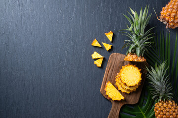 Wall Mural - Fresh cut pineapple with tropical leaves on dark blue background.