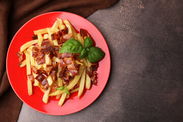 Wall Mural - Delicious French fries with bacon and basil on brown background, top view. Space for text