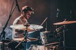 © Jiraphat - A young drummer passionately plays his kit on stage, surrounded by vibrant lights, capturing the audience's attention during an electrifying live performance