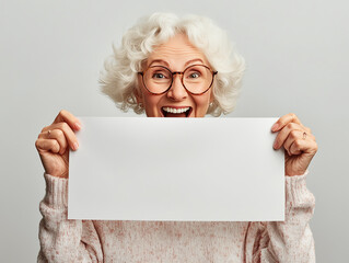 Joyful senior woman holding blank sign, smiling cheerfully in bright indoor space